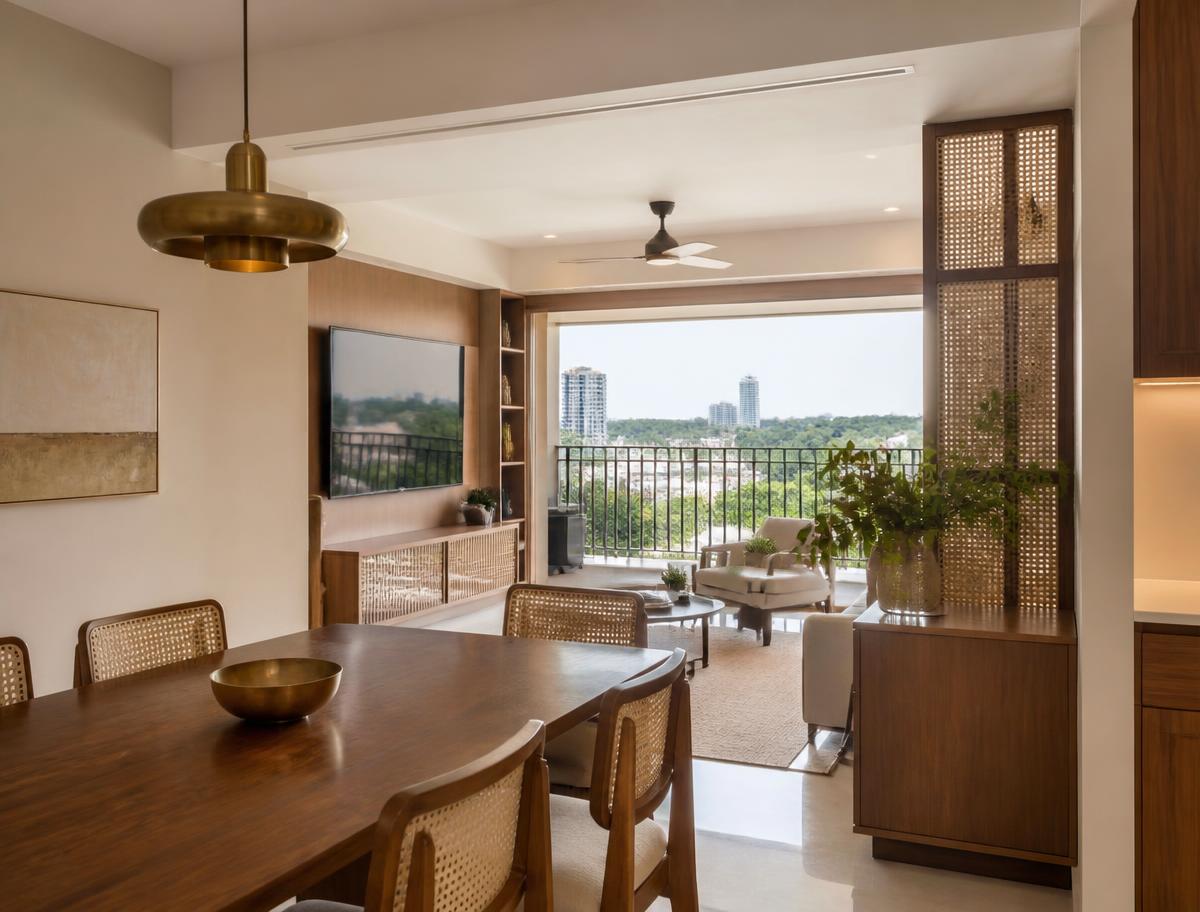 Modern Indian high-rise apartment living and dining space with teak, cane and brass detailing